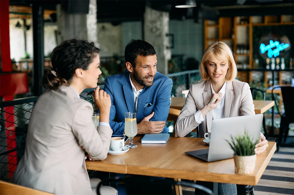 group of colleagues using laptop during business meeting in a cafe